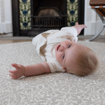 baby rolling on floor mat playrug that looks like a rug but a foam play mat in acorn design from morris & co collaboration with totter and tumble