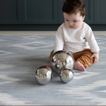 Baby sitting and playing with sensory toys on Light blue and beige play mat with subtle diamond design inspired by ikat motifs ideal for family living spaces