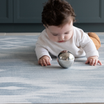 Baby laying on Childrens play mats the whole family will enjoy The Atlas has a striking Ikat design that looks like a rug in the home available in four sizes so you can unroll just where you need it