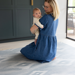 Mom and baby sitting on Thick padded play mats by totter and tumble are perfect for the smallest members of the family The Atlas has a hand drawn Ikat design in modern light blue and beige shades 