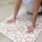 mother doing exercise stretches on totter and tumble runner play mat whilst baby sleeps