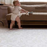 baby pulling up on sofa to standing on large padded play mat