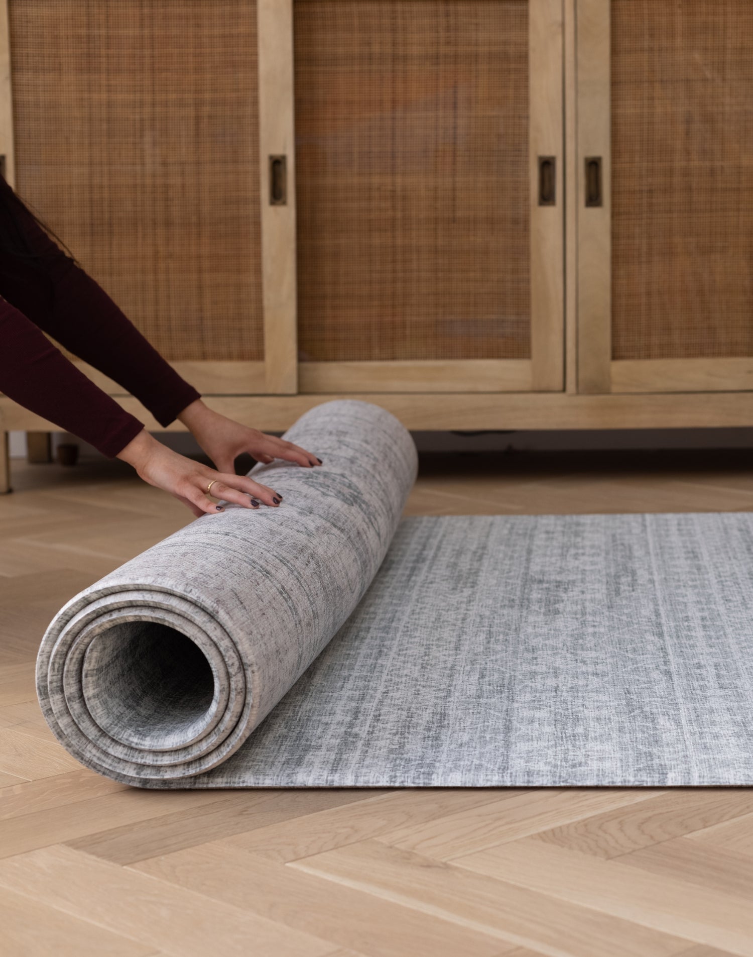 Hands roll out a large non slip mat that looks like a stylish rug