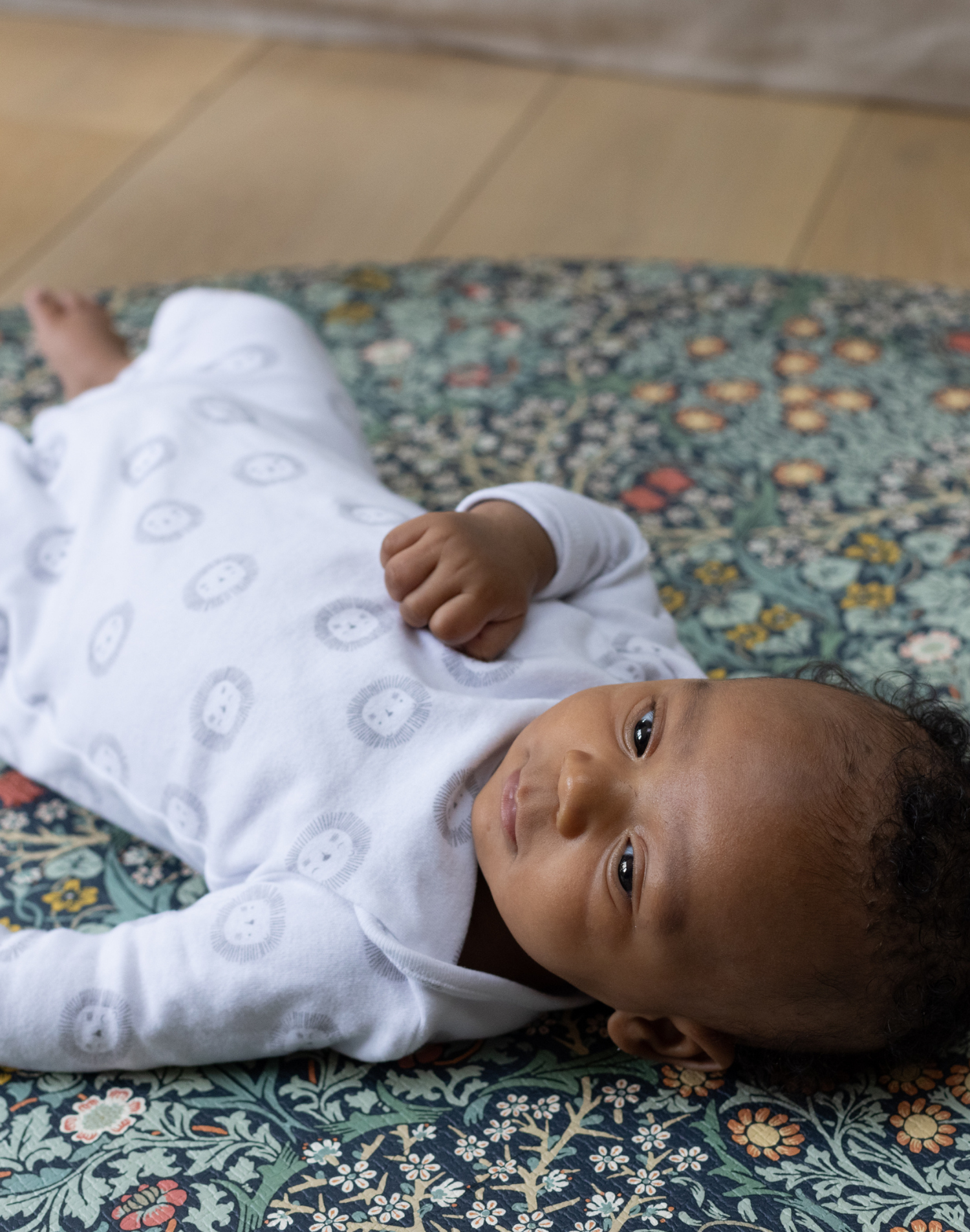 morris & co totter and tumble blackthorn play mat in round size with baby resting on a soft and supportive foam surface playrug that is a padded play mat floor mat that is non toxic and safe from newborn+