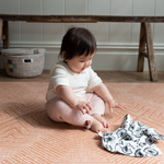 baby girl plays on kids play mat with a stylish orange design