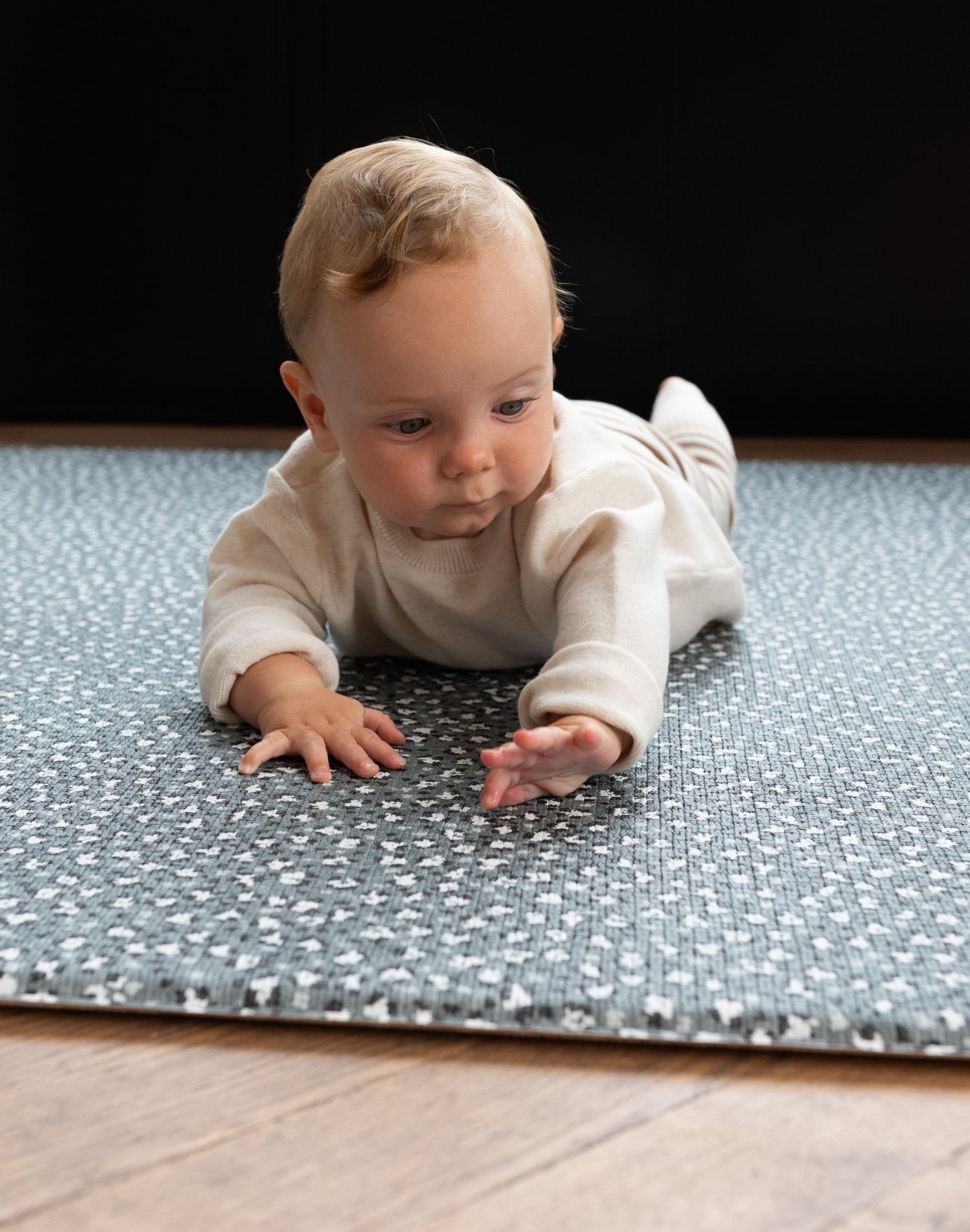 Baby lays on tummy on supportive play rug with leopard print design