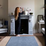 Lady arranges floral display within a comfortable living room a totter and tumble kids play mat is on the floor