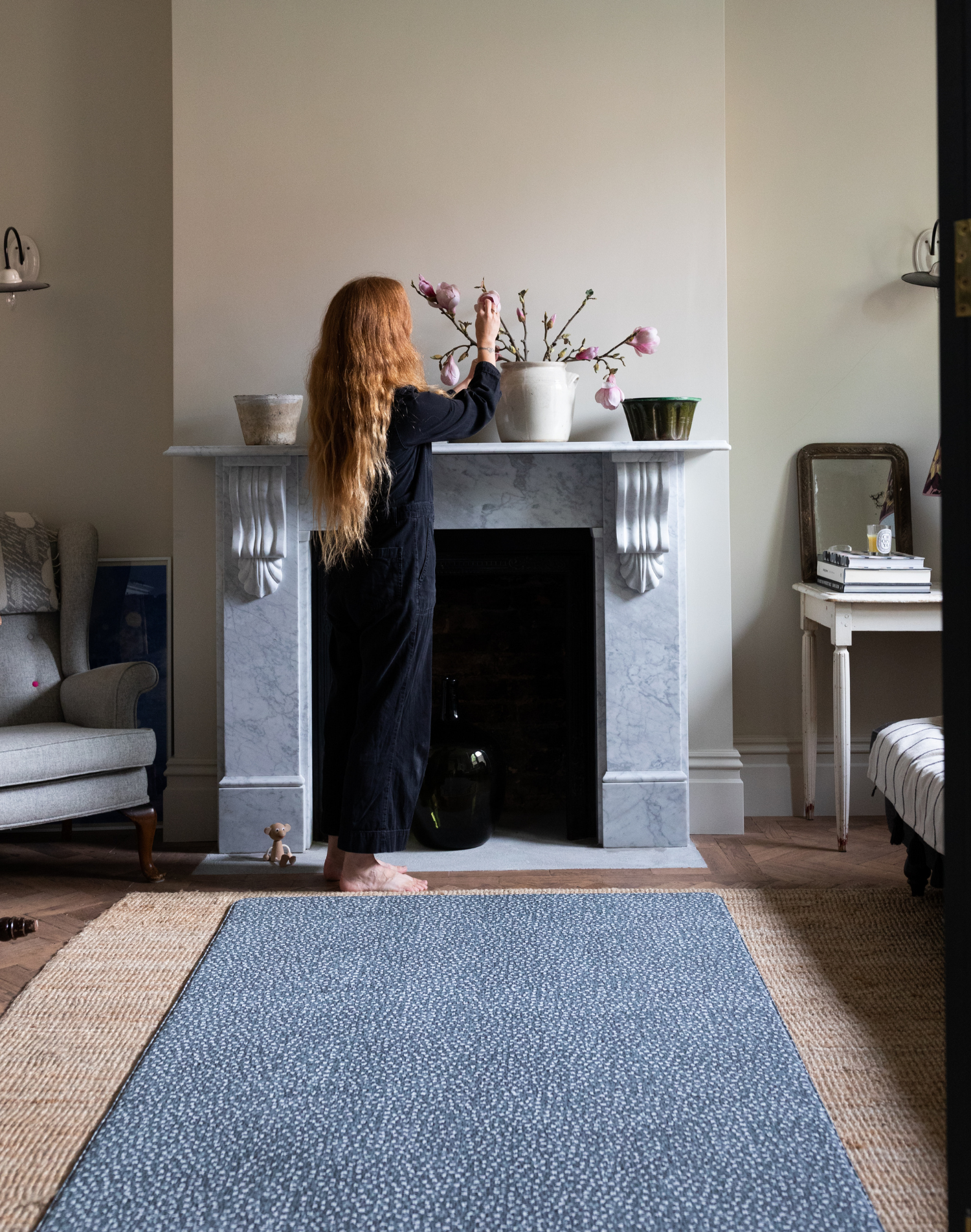 Lady arranges floral display within a comfortable living room a totter and tumble kids play mat is on the floor