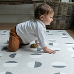 child enjoys playing on foam play rug created with an organic polka dot motif for a modern decor look in the family home.