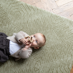 Baby enjoys floor time on the cushy play rug with a stylish olive textile design