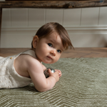 Baby enjoys sensory floor play on one piece memory foam play rug in a modern olive colorway