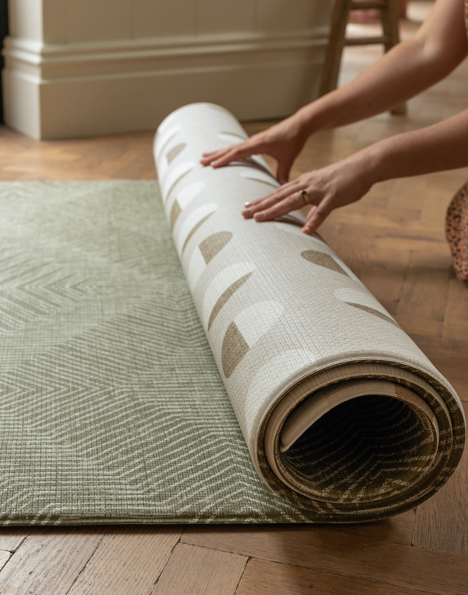 Hands unroll the play rug with two designs in chic colors to complement your stylish family interior