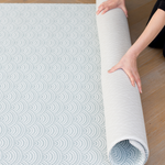 Unrolling a double sided memory foam baby floor mat that is designed for modern family spaces including a scalloped motif and on the reverse a geometric chevron