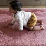 Large crawling play mat in a deep red tone with baby girl crawling across the protective and padded foam surface for safe and comfortable play time on any type of flooring