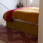 Red runner mat is placed alongside vibrant bed to create a soulful sanctuary in a bedroom and adding protection and comfort when climbing in and out of bed while also being the ideal prayer mat and exercise mat