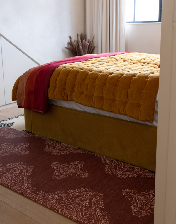 Red runner mat is placed alongside vibrant bed to create a soulful sanctuary in a bedroom and adding protection and comfort when climbing in and out of bed while also being the ideal prayer mat and exercise mat