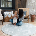 Mom and baby on Round play mat for hard floors by Totter and Tumble so little ones don't feel the floor underneath with stylish green and beige ikat design for a stylish look 