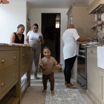 family gathering in the kitchen with toddler and mother using totter and tumble play runner to cushion their feet