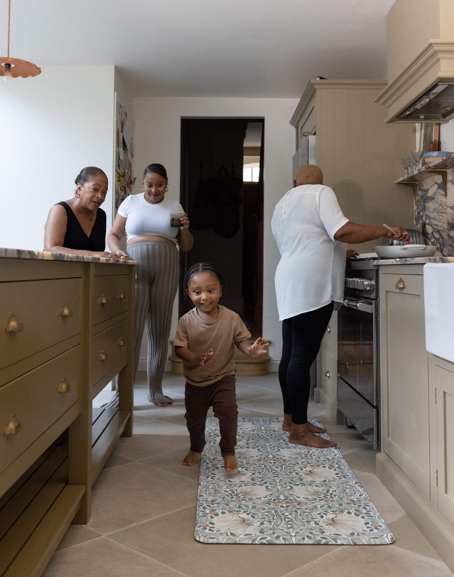 family gathering in the kitchen with toddler and mother using totter and tumble play runner to cushion their feet