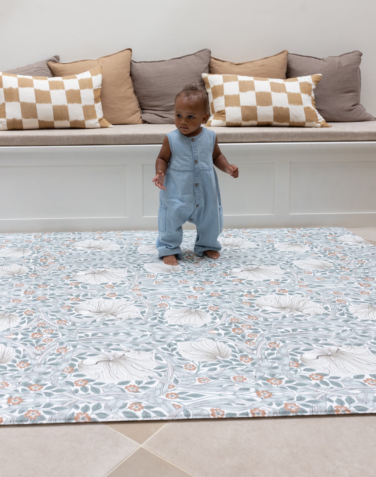 Baby standing on padded totter and tumble play mat from Morris and Co Collaboration