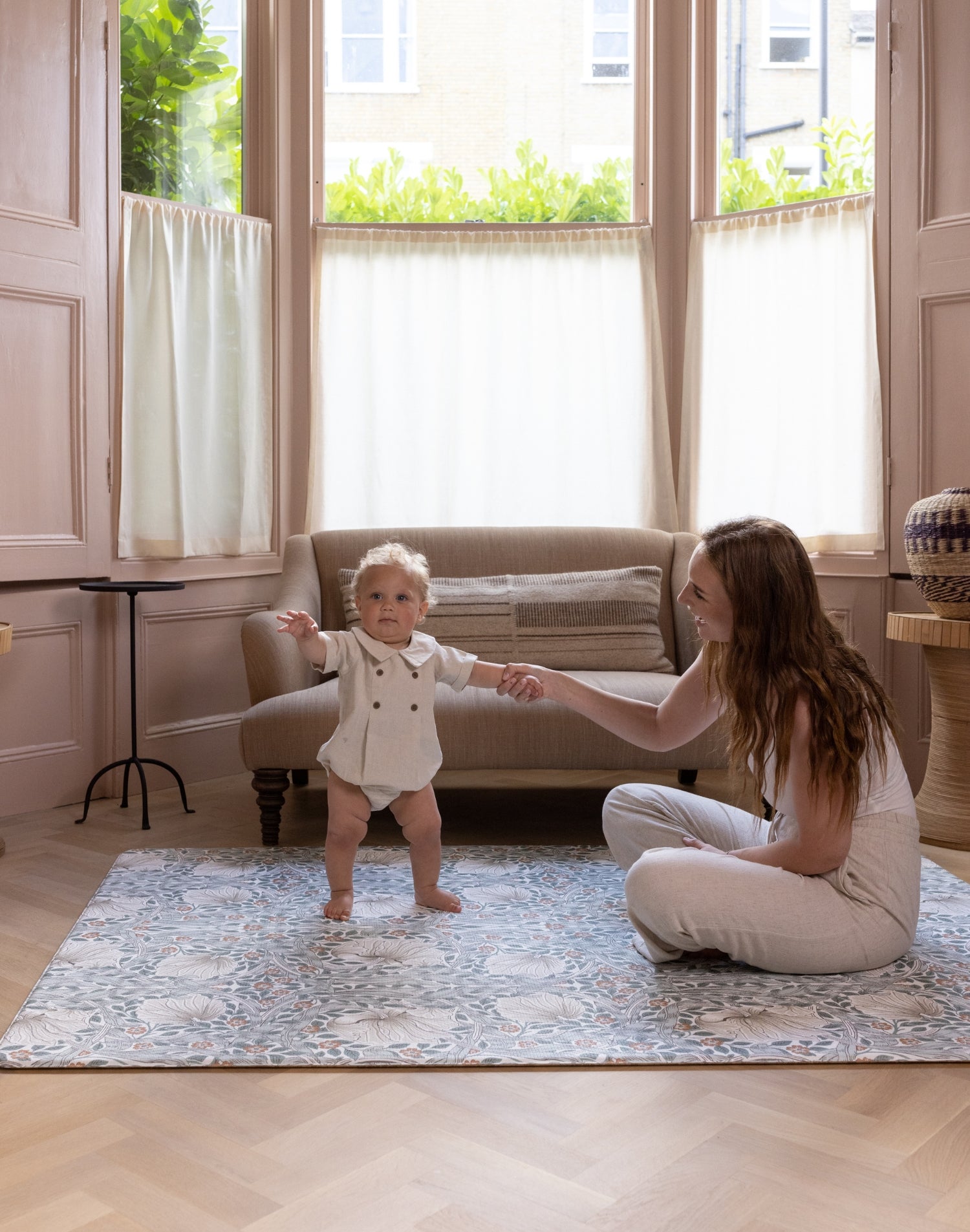 Baby standing on padded totter and tumble play mat from Morris and Co Collaboration