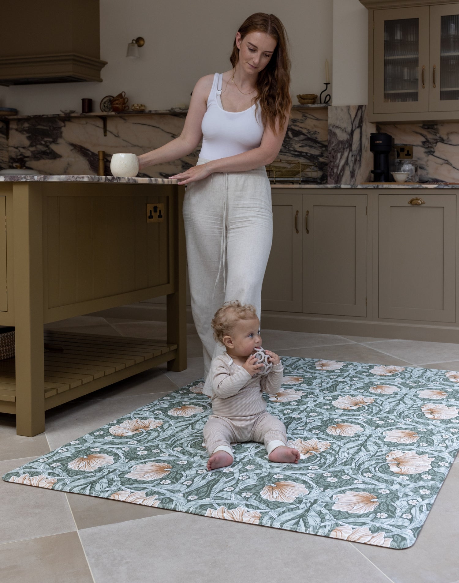 Mum and baby in family kitchen using padded play mat with Morris Pimpernel in green