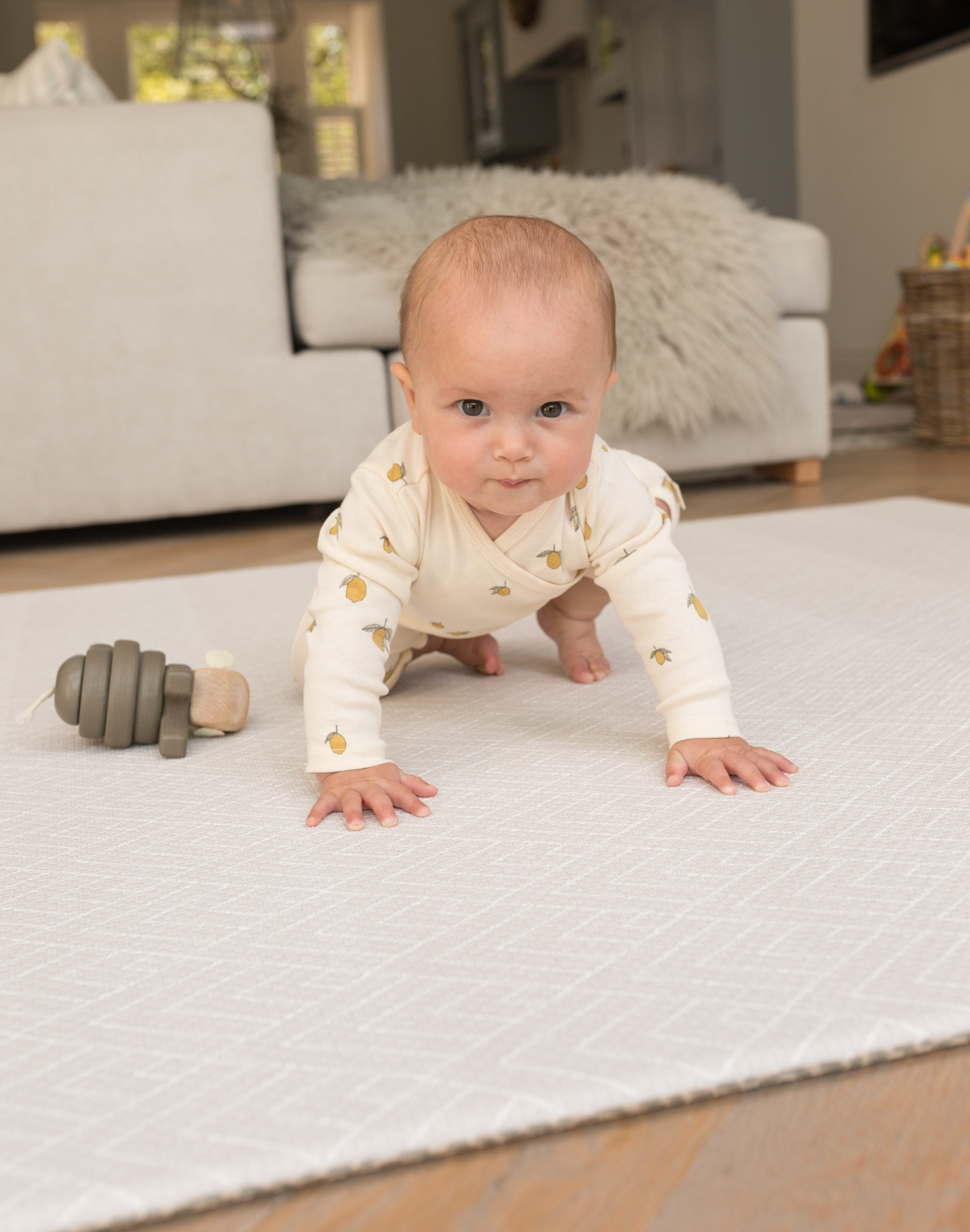 Baby resting on thick floor mat with wooden toy