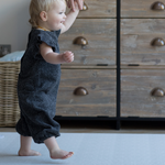 Toddler walks across thick play mat holding hand of adult for extra support