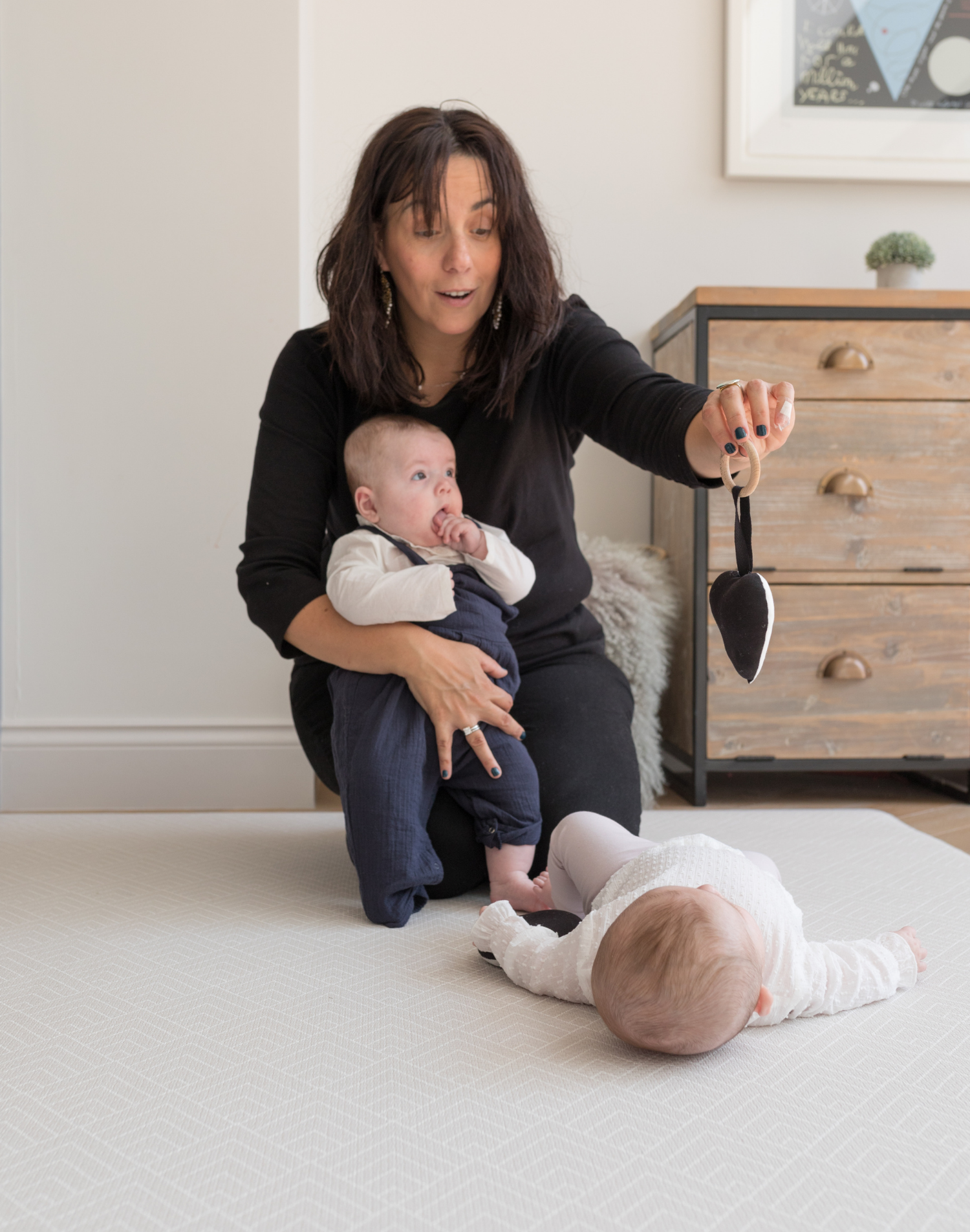 Lady and two babies enjoy time playing comfortably together on a neutral chevron play mat that sits subtly in the space it is placed