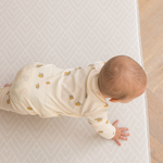 Baby crawls on thick memory foam play mat that makes movement more comfortable on hard wood flooring