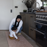 Mom and baby enjoy time together in the kitchen keeping comfortable on the kitchen mat rusa with a gentle leopard print that looks stylish with a thick memory foam design for comfort and protection on kitchen tiled flooring