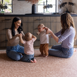 Babies and moms enjoy play time in the kitchen on the protective foam surface of the orange Rusa play mat designed to look beautiful in homes while allowing the family to take to the floor in comfort