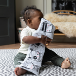 Baby plays with soft book supported on the ergo foam kids play mats with the iconic Scout design