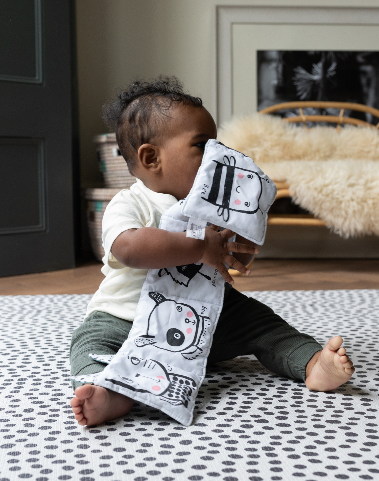 Baby plays with soft book supported on the ergo foam kids play mats with the iconic Scout design