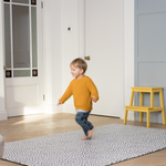 Little boy enjoys play time in the family home with a protective play mat rug