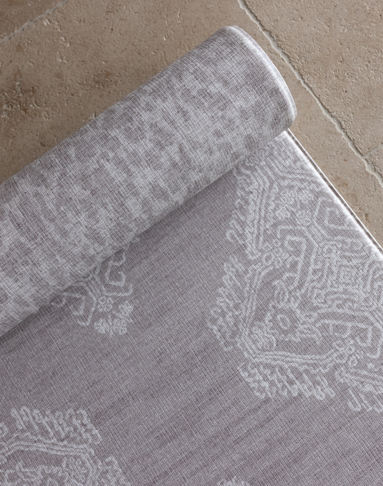 Close up of double sided gray play mat with intricate textile inspired design and a subtle animal skin motif on the reverse thick foam mat design provides comfort on hard tiled kitchen spaces  