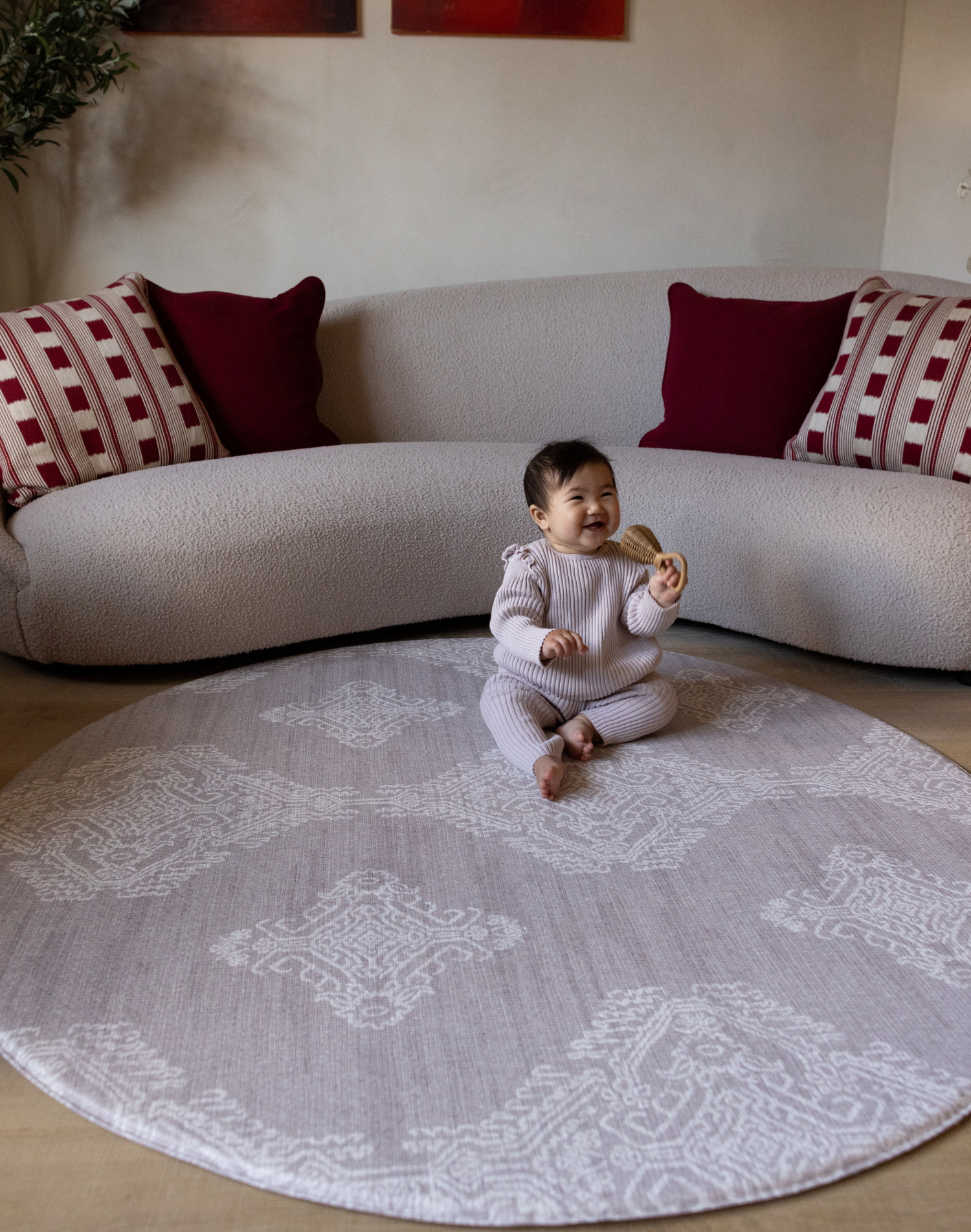 Baby sits on round gray sepi play mat with thick memory foam to support and protect from falls and tumbles