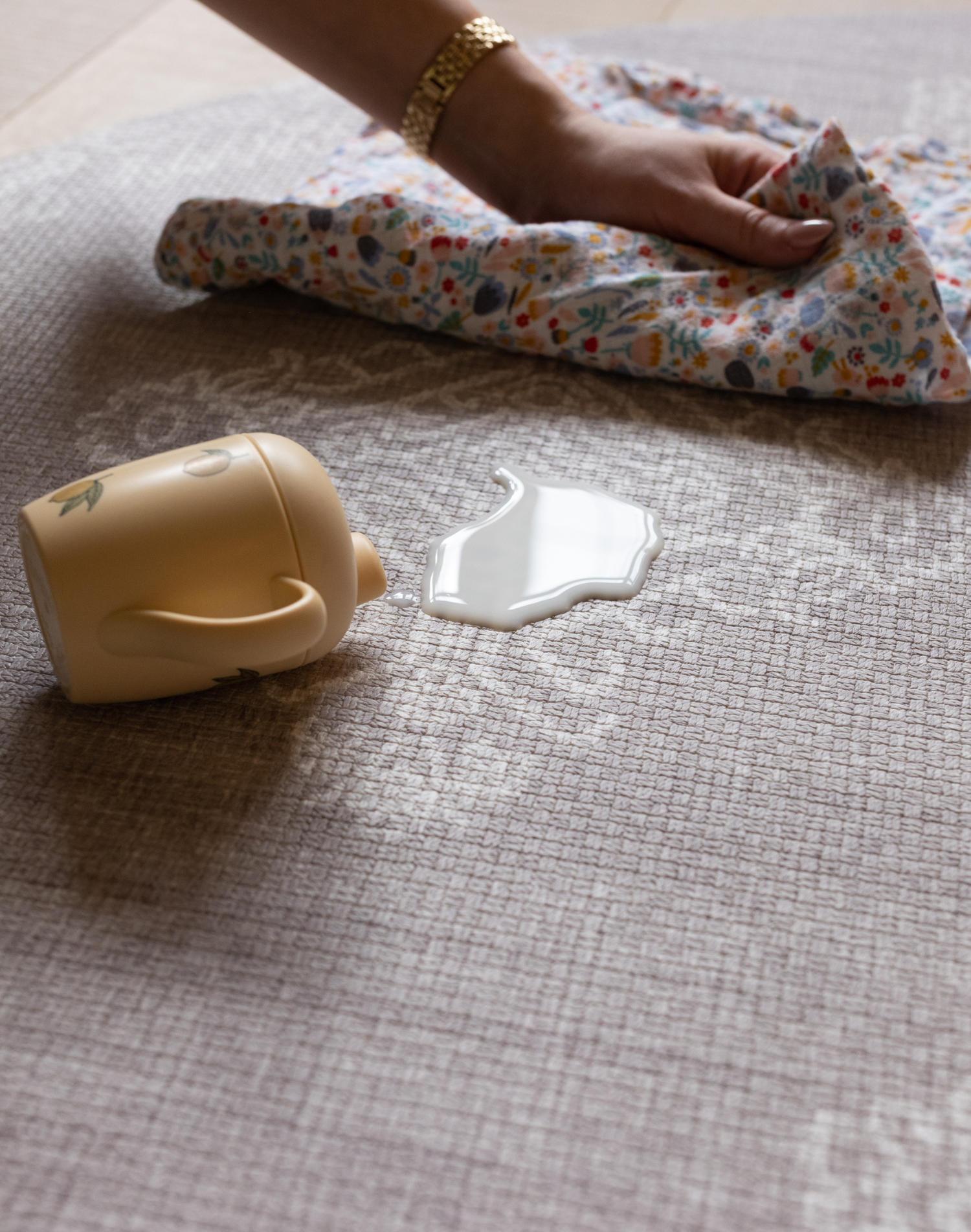 Hand wipes up milk spillage on sealed memory foam surface closed cell play mat design ensures cleaning is simple and doesn't harbor dust and dirt like textile rugs 