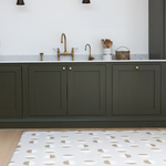 Neutral standing mat with a modern solstice design looks stylish against deep green kitchen carpentry