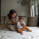 Mother and child enjoy play time in comfort on a durable play rug that has a modern look with stylised solstice motif