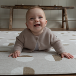 Baby lays on foam tan floor mat with non toxic materials that are safe from birth