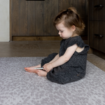 Toddler sits comfortably on cushy gray play mat with a modern neutral play mat design that looks stylish in large family kitchen spaces 