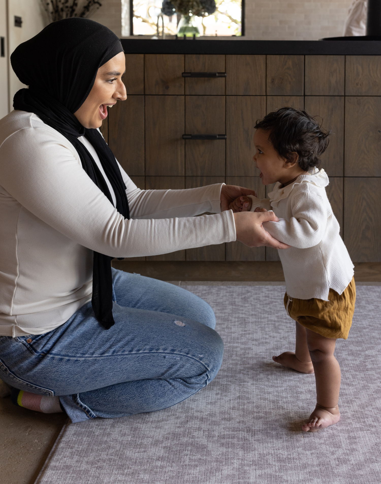 Mom and baby enjoy floor time on subtle animal print play mat the sunda by totter and tumble a modern gray play mat design for a stylish look in the home 