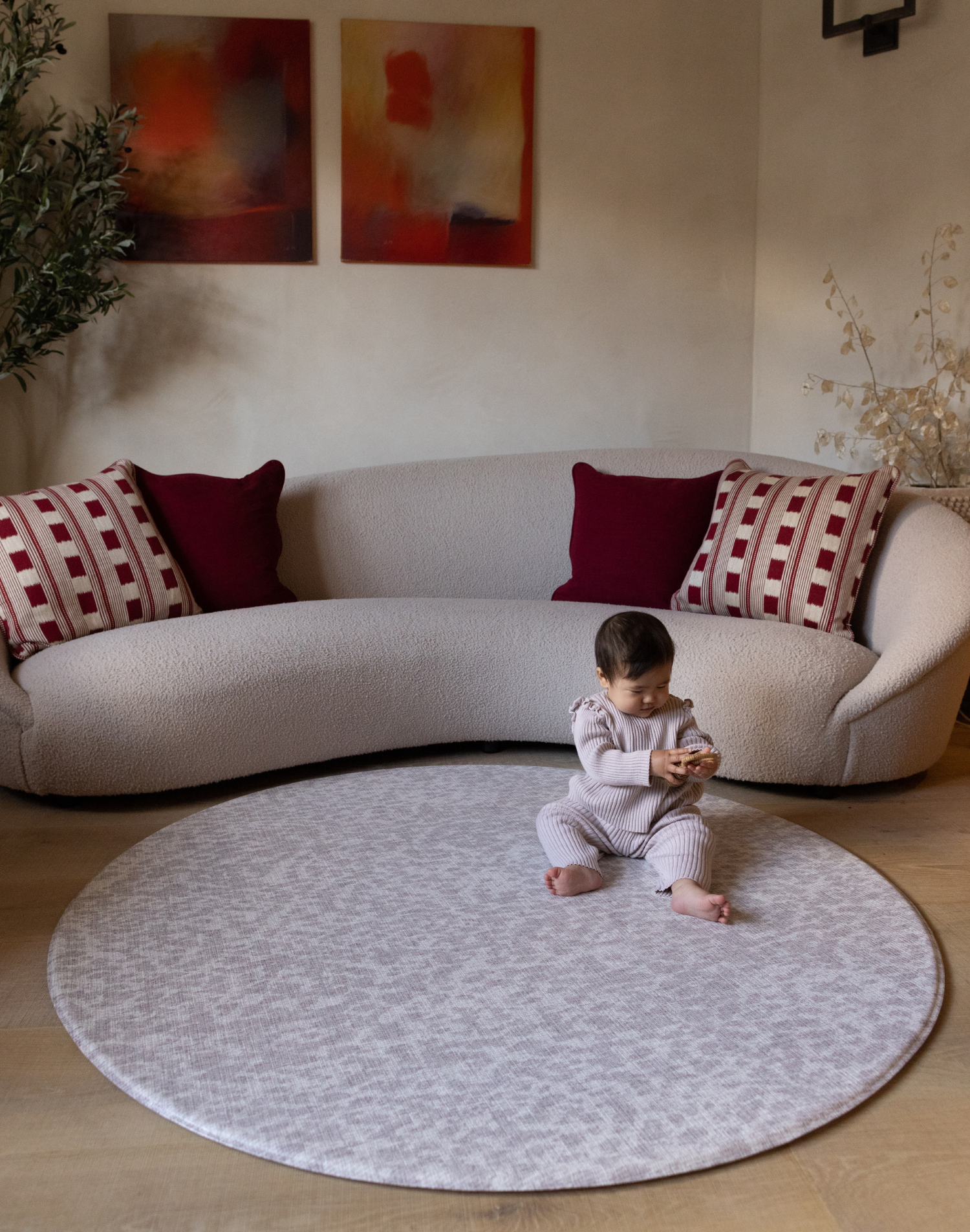 Baby sits on large round gray play mat the sunda a portable play mat size for anywhere in the home with supportive foam design to protect from tumbles and falls