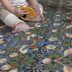 Baby sitting and playing on thick memory foam play mat by Totter and Tumble with Strawberry Thief design from William Morris archive supportive and protective for babies development