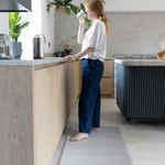 Lady drinking and standing on the Foam runner for support underfoot in the home ideal as a kitchen runner or exercise mat The Tali design has a neutral appeal 