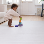 Toddler stacking wooden toys on the Tumble mats in tan and beige ombre design for support during floor play