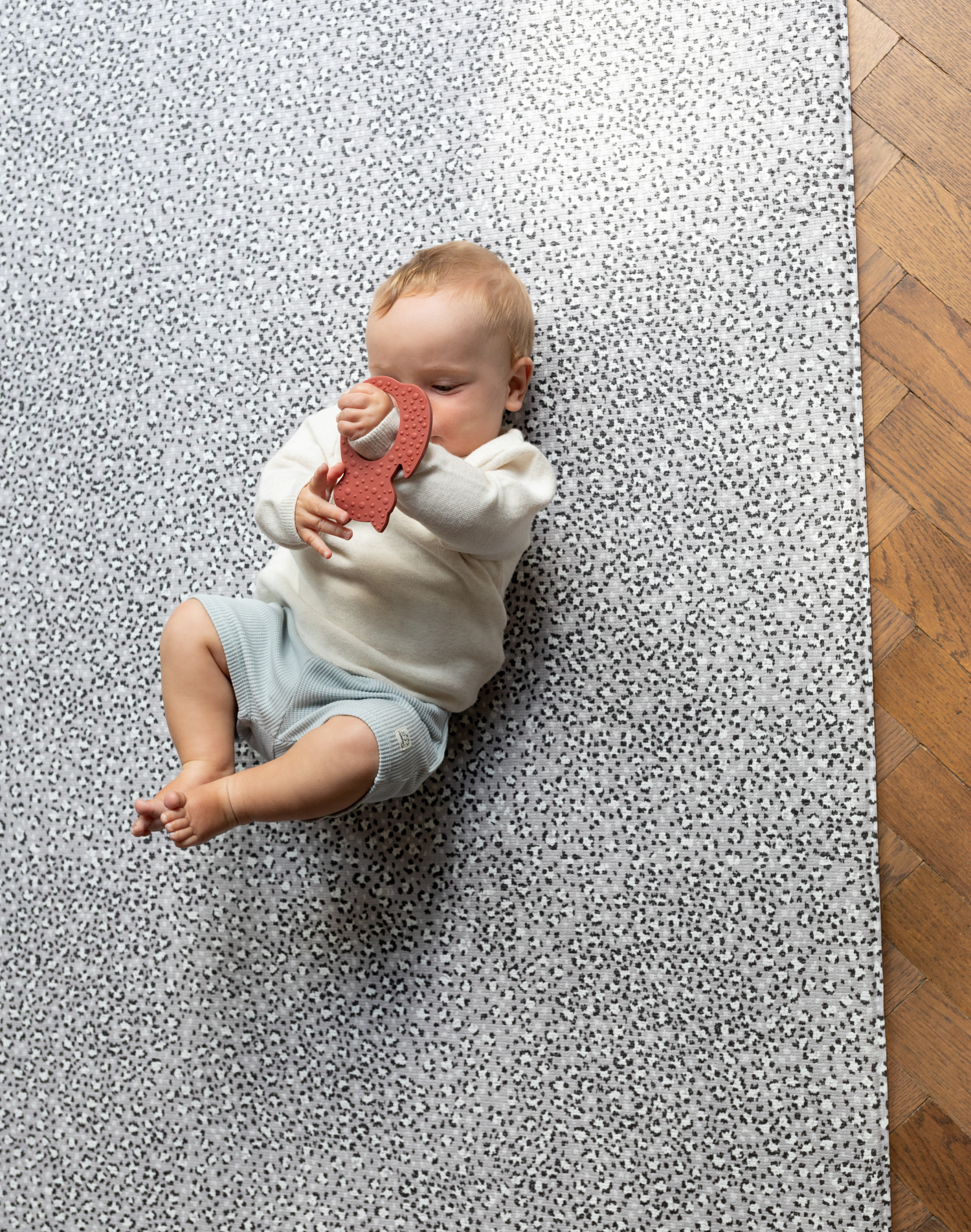 Baby lays on foam baby play mat with modern leopard print motif