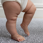 Baby stands on the cushy foam play mat with thick memory foam to asborb shocks and provide comfort