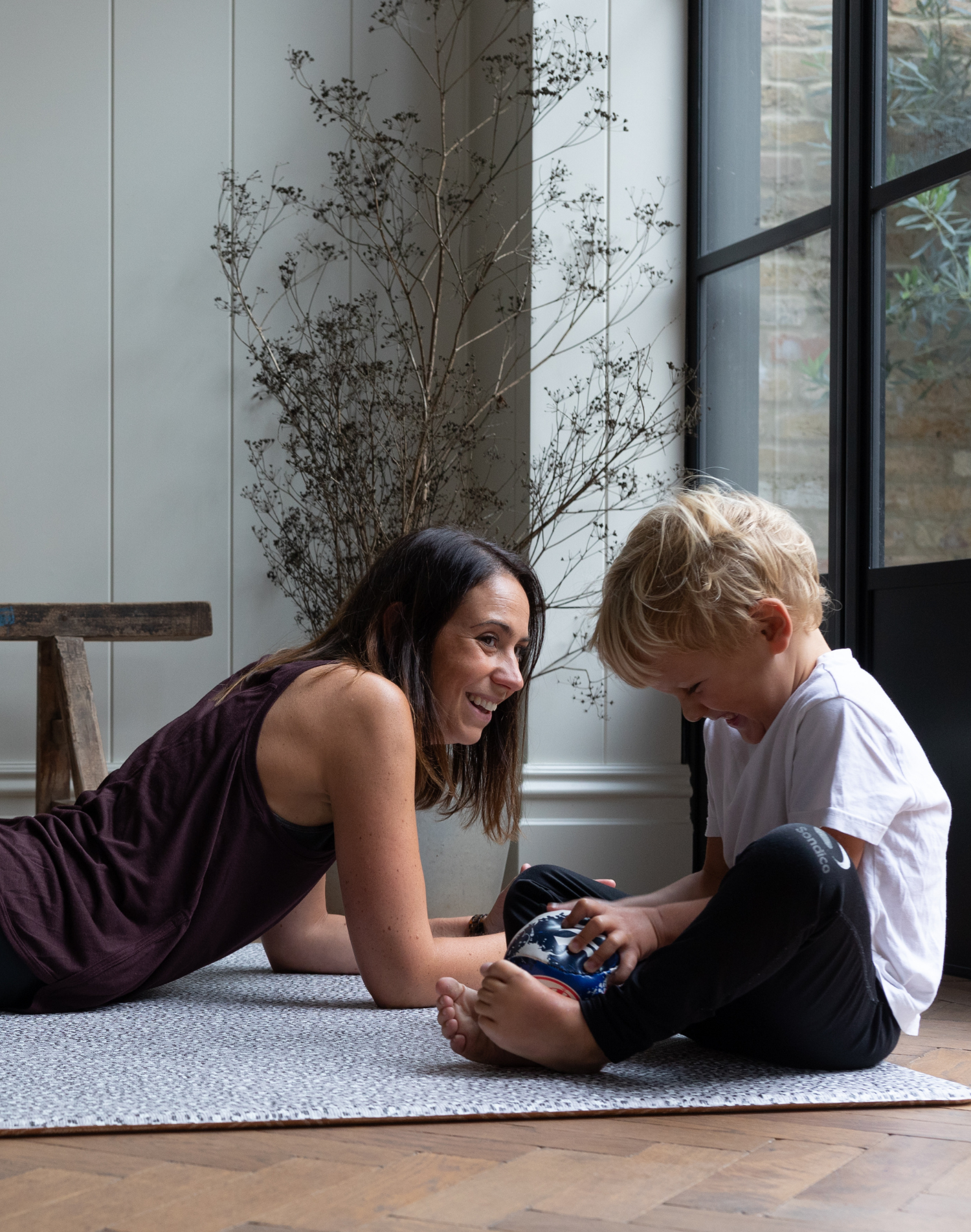 Mom and son relax together on foam kid play mats with a modern grey leopard design